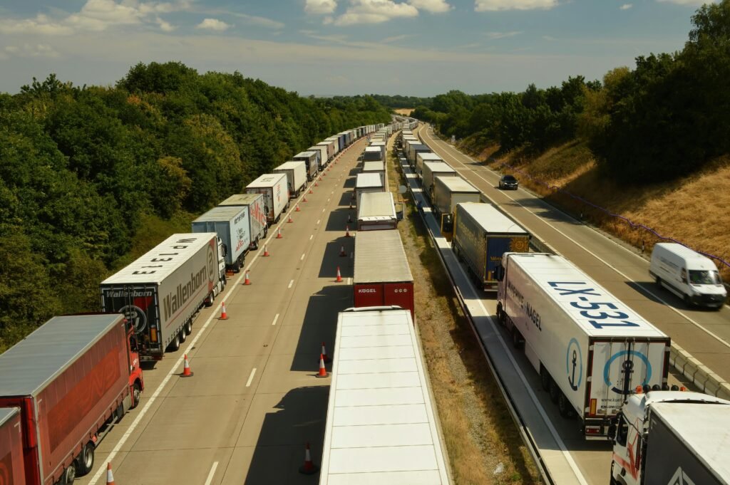 A high-angle shot of trucks and trailers in traffic on a highway in England beneath a bright sky.