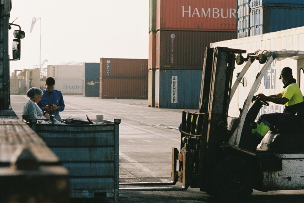 Workers operating a forklift in a shipping container yard at Praia port, Cabo Verde.