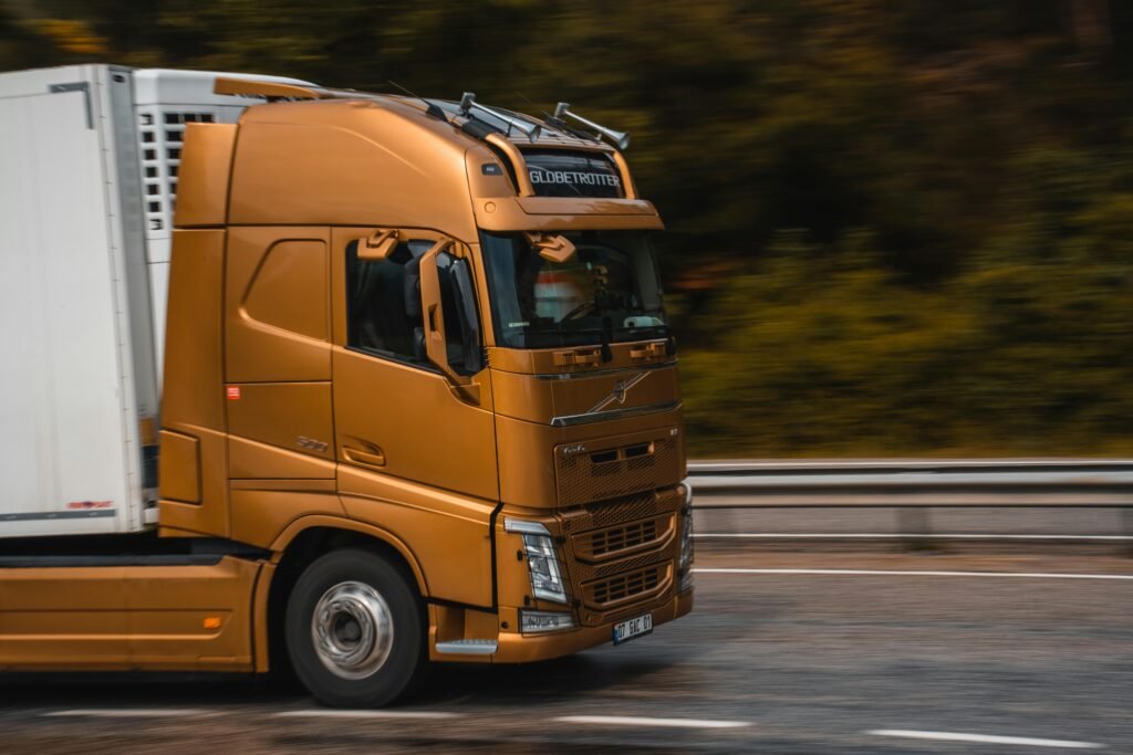 Orange truck speeding along a highway in Kemer, showcasing transportation and logistics.