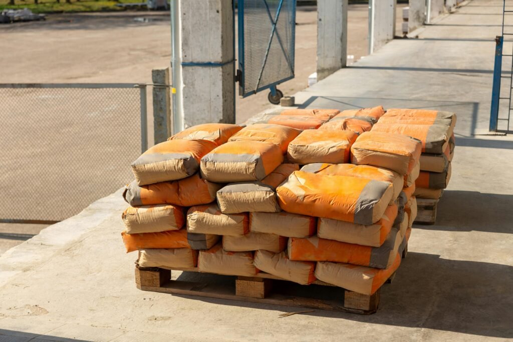 Pile of orange cement bags on a wooden pallet in an industrial setting.