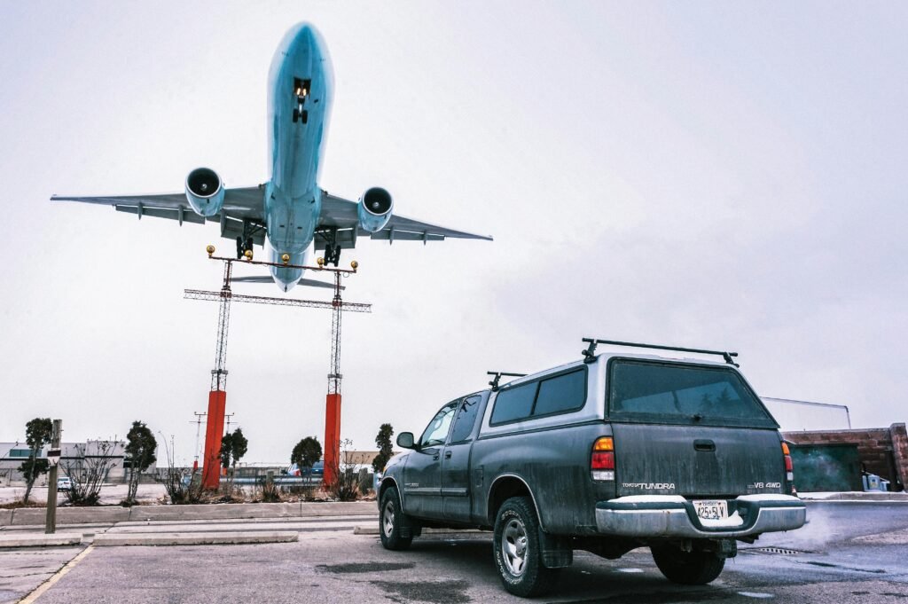 A striking image capturing an airplane landing closely over a parked truck on a tarmac.