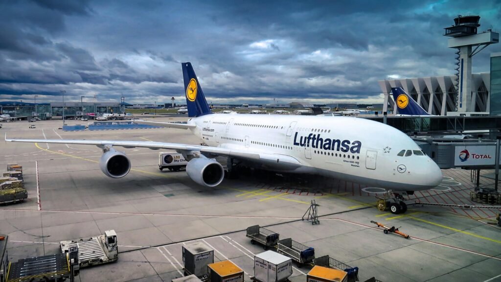 Lufthansa Airbus A380 parked at the airport gate, ready for departure under a dramatic cloudy sky.