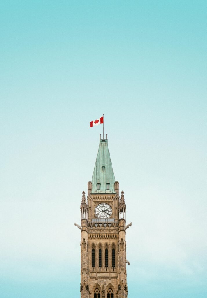 The iconic Peace Tower in Ottawa, Canada, with a clear blue sky and Canadian flag.