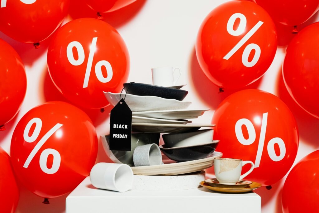 Red balloons with percentage signs surround dishes, highlighting Black Friday sales.