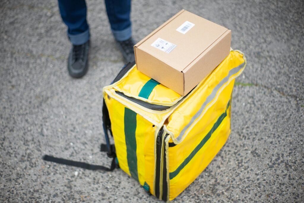 Yellow delivery bag and package on concrete with courier. Ideal for delivery service concepts.